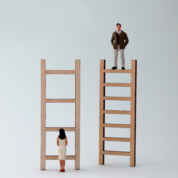 Image: miniature figures of a woman and a man. Both have a ladder in front of them, but the woman's ladder has fewer rungs.